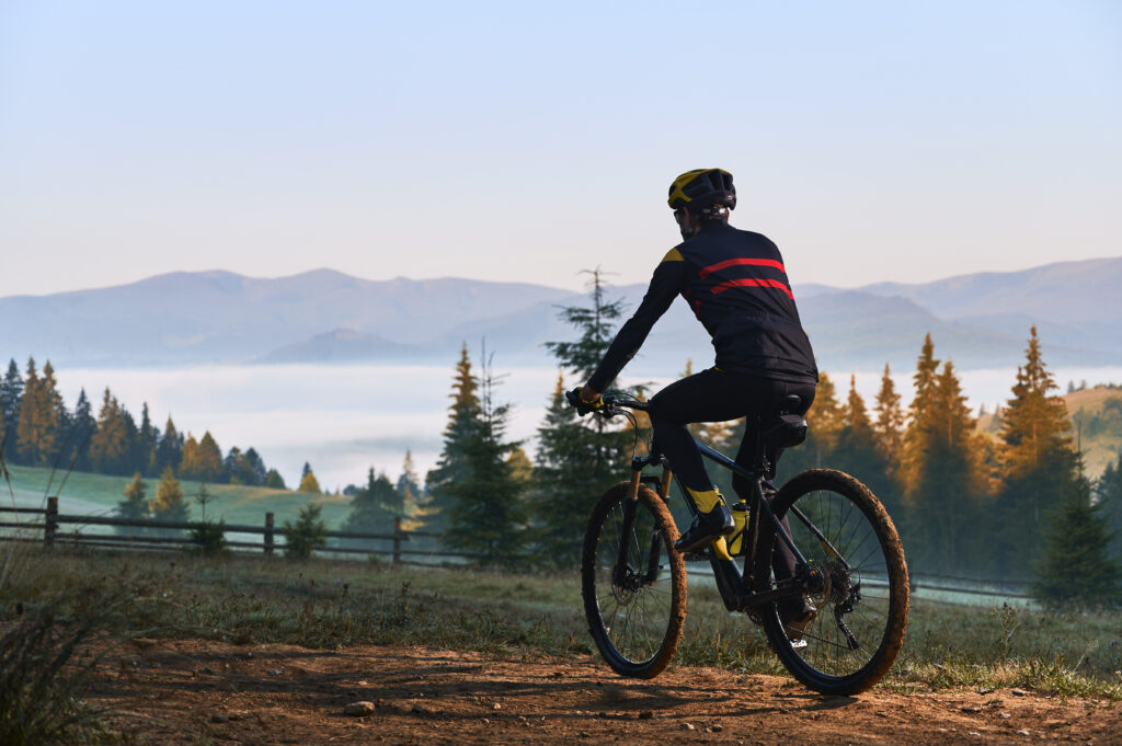 Smiling young man riding bicycle on mountain road.
